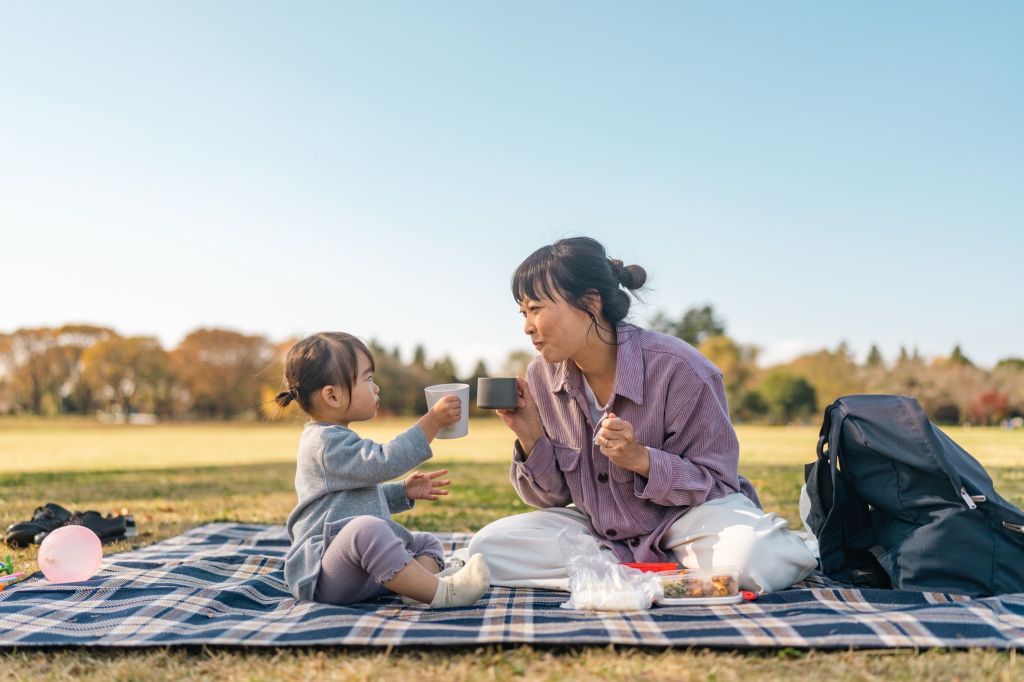 Woman and child sitting on picnic blanket